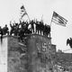 Men of the 45th division of the U.S. 7th Army wave American flags from the dais of the Luitpold Arena in Nuremberg, where annual Nazi party rallies were held.